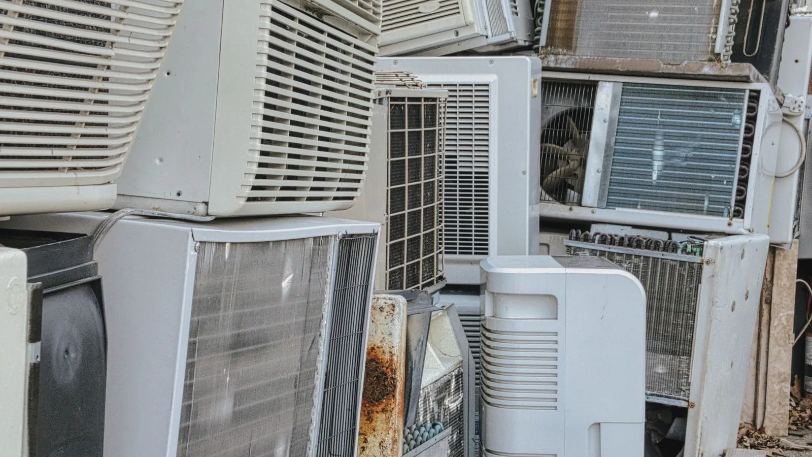 Timbunan unit aircond lama yang telah dilucutkan, kipas dan gegelung terdedah, disusun di luar - bahagian bergerak inilah yang menyebabkan aircond berbunyi bising.