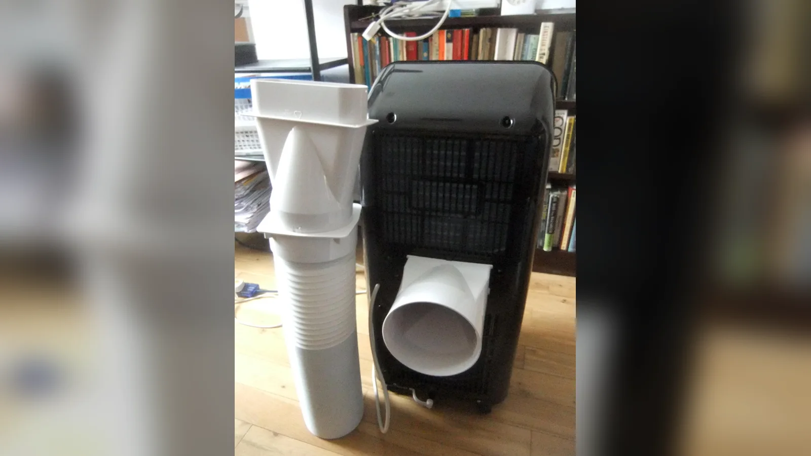 Bahagian belakang portable aircond dengan penyesuai hos dipasang, muncung tingkap dan hos ekzos di sebelahnya, sedia untuk dipasang.